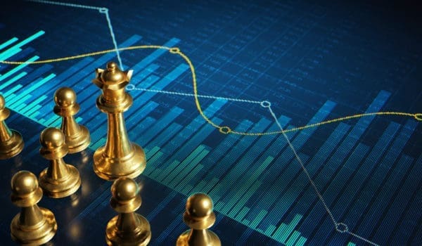 Golden chess pieces on a digital display with abstract financial charts and graphs