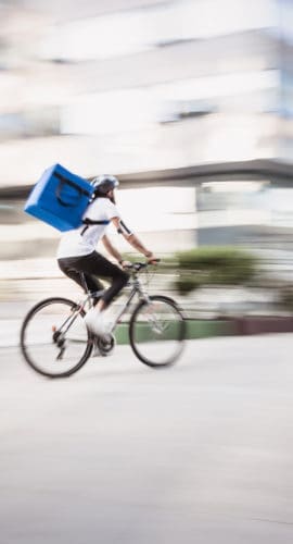 Food and supplies delivery man in motion blur. He is rushing on a destination in a downtown district. Belgrade, Serbia