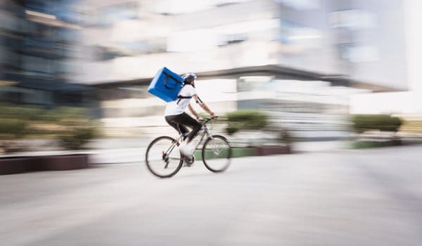 Food and supplies delivery man in motion blur. He is rushing on a destination in a downtown district. Belgrade, Serbia