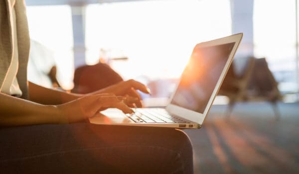 Unrecognizable young woman uses laptop while waiting for an early morning flight.