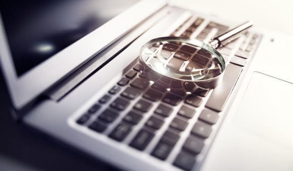 Magnifying glass on laptop keyboard searc for online documents background