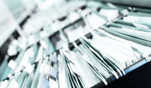 Multiple rows of filing cabinets in an office or medical establishment, overflowing with files.  Narrow depth of field to emphasize the "neverending" feeling