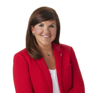 A person wearing a red blazer and white shirt smiles against a white background.