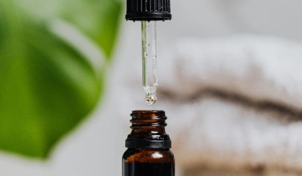 Person holding a dropper of brown bottle