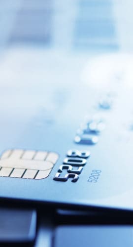 Blue tinted image of credit card on laptop with shallow depth of field.