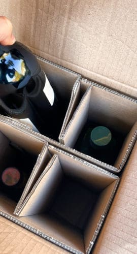 Menthon saint Bernard, France - October 16 2021: a person is taking a bottle of wine ordered on the internet out of a delivery box