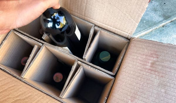 Menthon saint Bernard, France - October 16 2021: a person is taking a bottle of wine ordered on the internet out of a delivery box