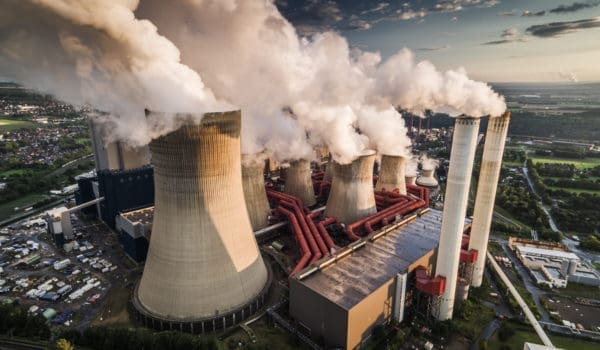 Aerial view of building exterior of a coal fired power station. Large cooling towers emitting steam into to air. Great for global warming, climate change and pollution themes.