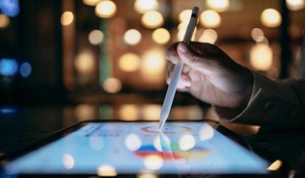 A businessperson is using a stylus to edit work reports on a tablet computer, which, combined with a mobile device, allows them to work more smoothly.