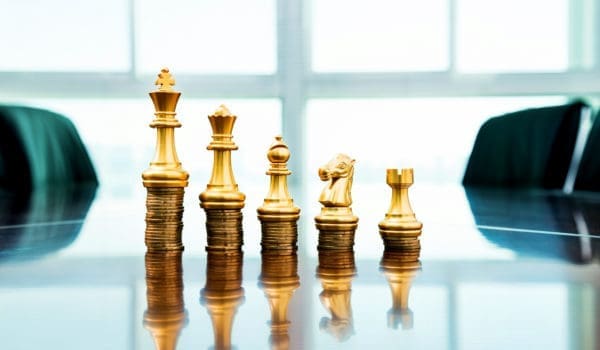 Chess pieces standing on the stacked coins.