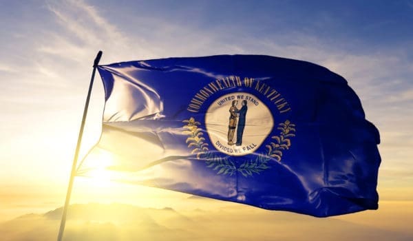 Kentucky state of United States flag on flagpole textile cloth fabric waving on the top sunrise mist fog