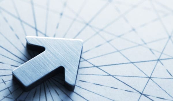 An arrow, photographed with a very shallow depth of field, sits on top of an old map lined with compass lines and navigational aids.