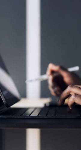 Unrecognizable African-American business woman typing notes on a keyboard while having online web conference on a digital tablet in a restaurant