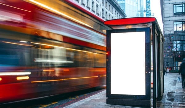 A blank billboard at a bus station at night