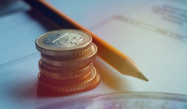 The real estate or residential concrete and wooden frame construction 3d model on blueprints and house the keys to the apartment a stack of coins.