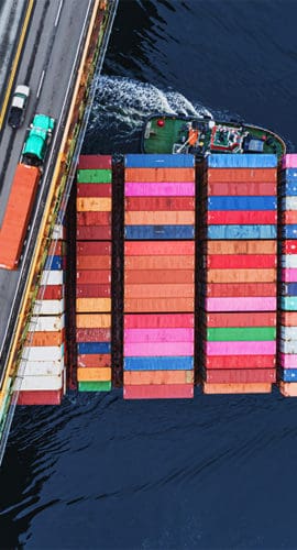 shipping containers traveling under bridge global economy