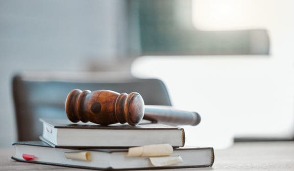 Justice, gavel and law books on table in office for court trial, legislation or fair constitution by judicial system. Firm, closeup and legal hammer by information for corporate case in workplace.