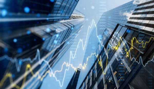 A double exposure image of skyscrapers with overlay of financial graphs, set against a blurred background, illustrating the concept of business growth