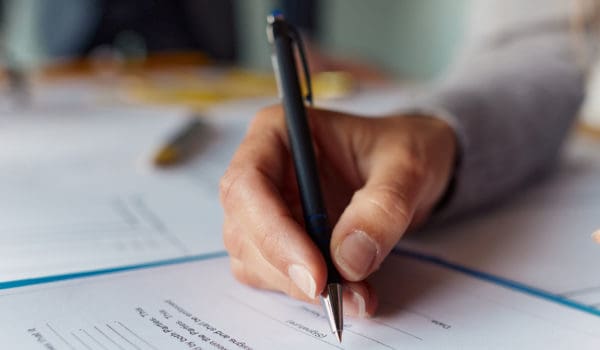 Close up of unrecognizable woman signing a contract.