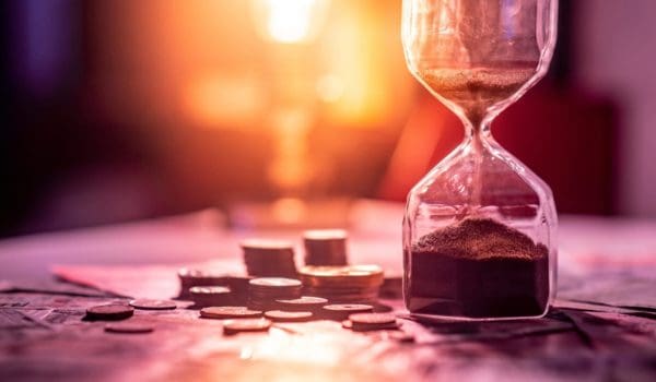 Hourglass with coins representing time-sensitive 1031 exchange and sale-leaseback real estate investment strategies