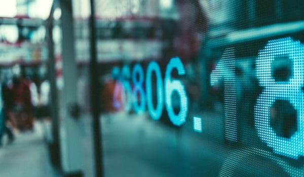 A close-up view of a digital display showing stock market data, illuminated in a bustling urban environment, emphasizing finance and business concepts.