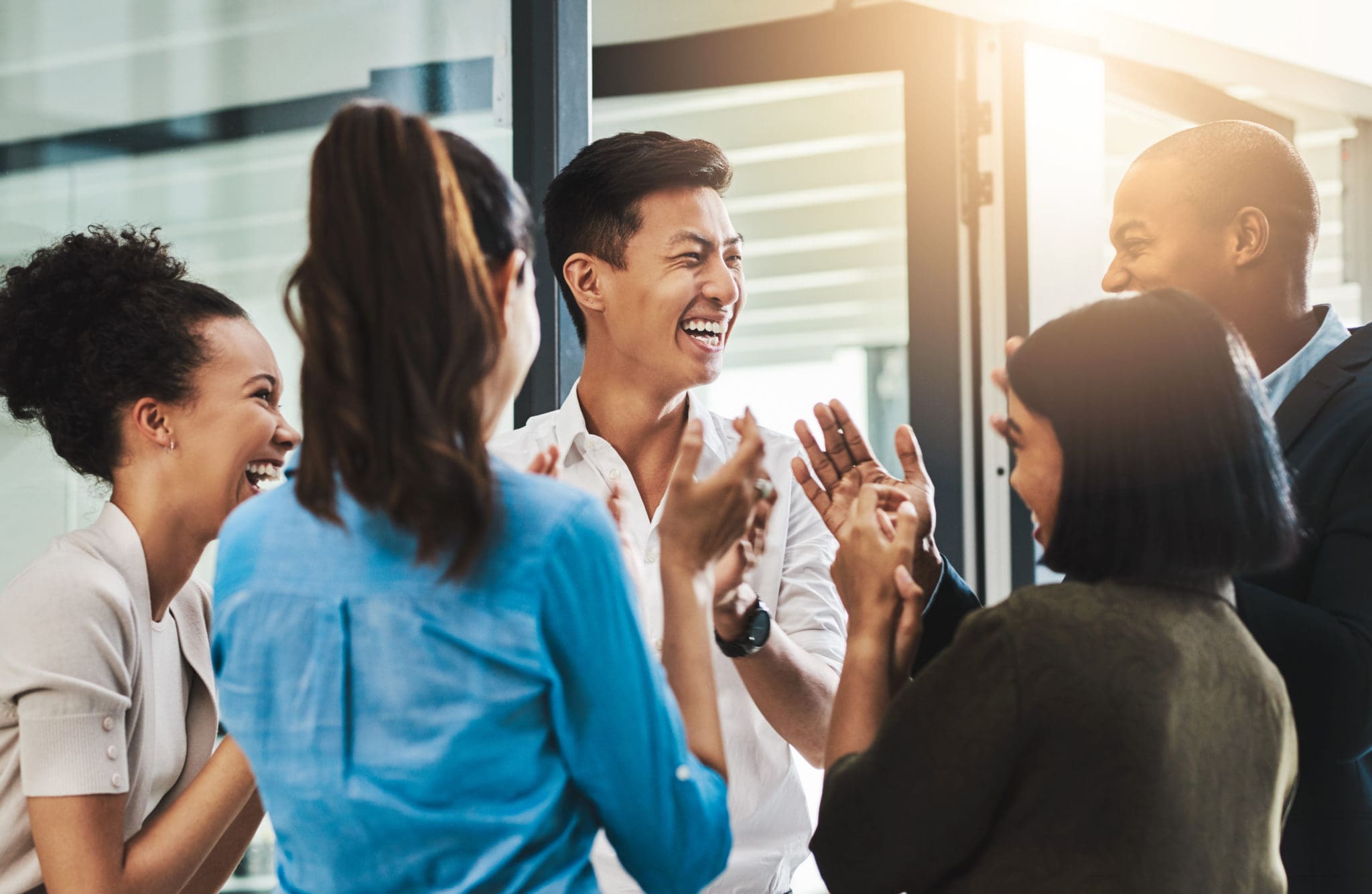 Shot of a group of young businesspeople standing together and clapping in a modern office