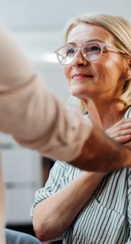 Senior woman being emotionally supported by a friend indoors. The photo showcases trust, warmth, care, and friendship in a modern home environment.